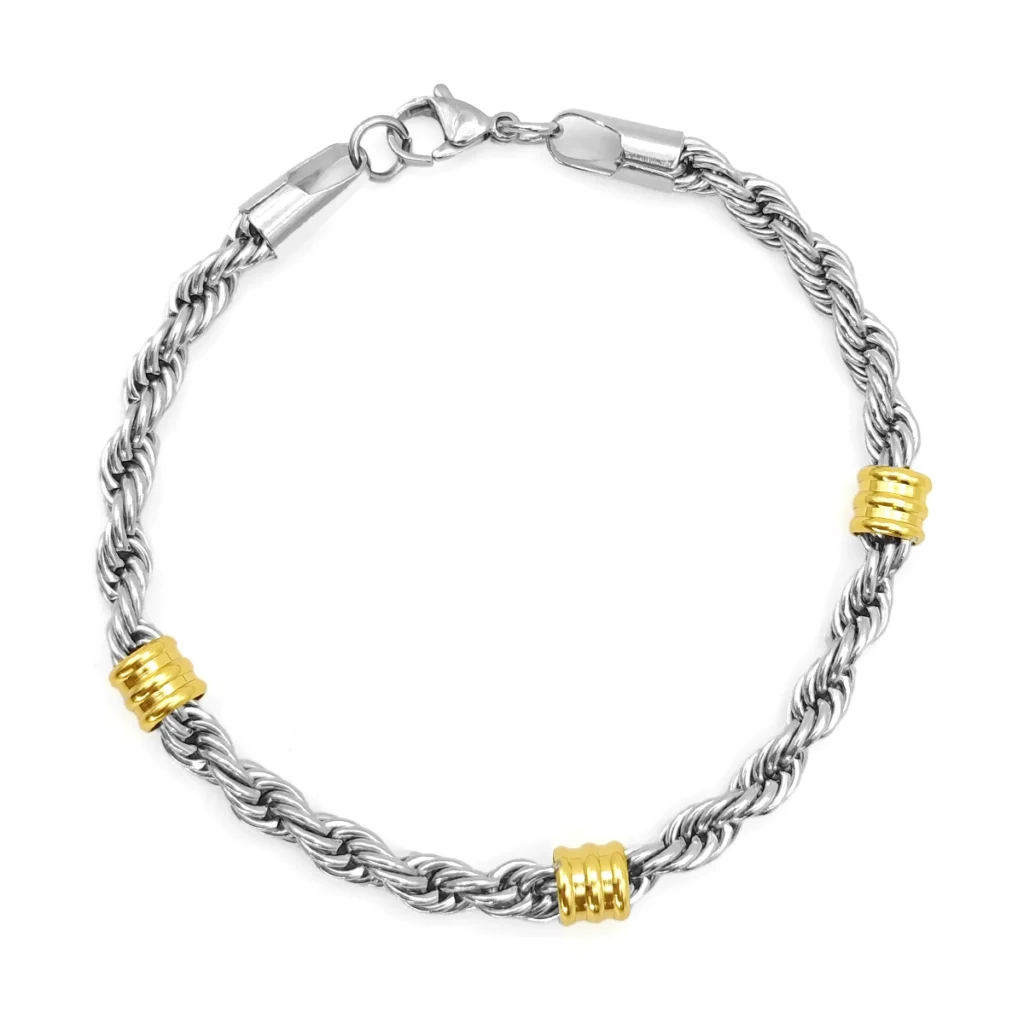 Pulsera bicolor de acero inoxidable tipo torzal con remaches tubo dorados sobre fondo blanco