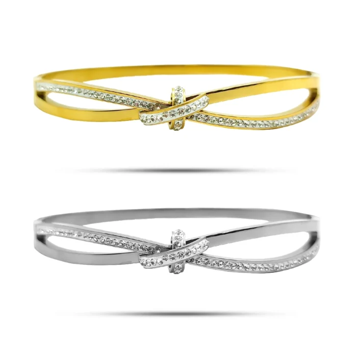 Brazalete de acero inoxidable con nudo cruzado y micro cristales en acabado dorado y plateado sobre fondo blanco