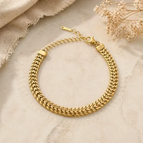 Pulsera cubana dorada de acero inoxidable con doble fila unida sobre fondo beige texturizado